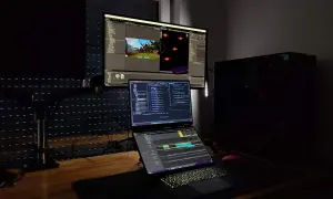 Stanowisko programisty z trzema monitorami, na których widać edytor kodu i scenę gry. Czy c.