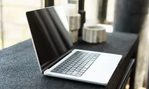 Nowy laptop czeka na pierwsze uruchomienie komputera. Na blacie obok stoją ozdobne świeczniki.