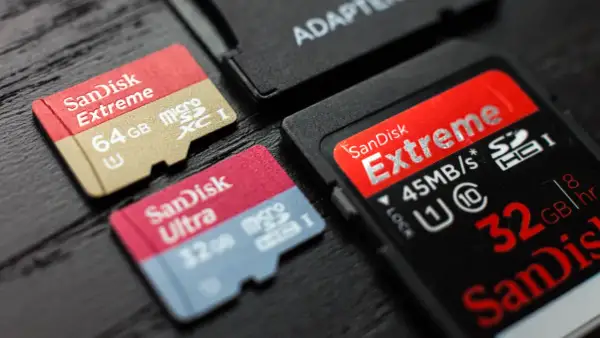 Karty pamięci SanDisk Extreme i Ultra, w tym 64GB microSDXC i 32GB microSDHC, obok adaptera. Różnice między SDXC a SDHC są widoczne.